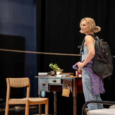 Rehearsal photo for Fy Enw i yw Rachel Corrie. A woman with a messy ponytail is wearing a backpack.