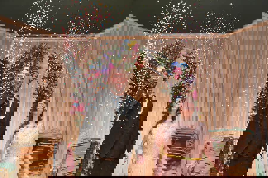 A man and woman in wedding attire throwing confetti