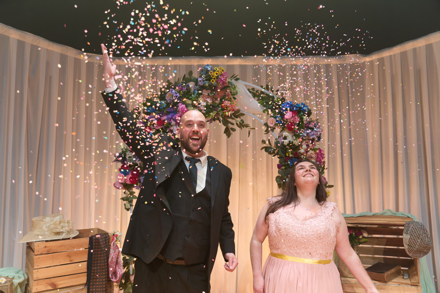 An image of a man and woman in wedding attire throwing confetti.