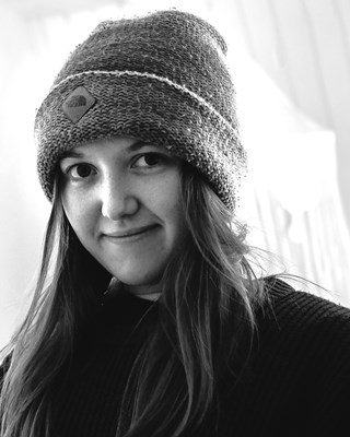 Hayley Egan Headshot, black and white filter. Wearing a beanie looking directly into centre frame of camera