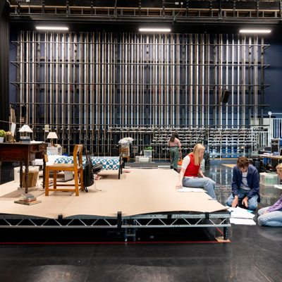 Rehearsal photo for Fy Enw i yw Rachel Corrie. A wide shot of the stage with people reading scripts and working.