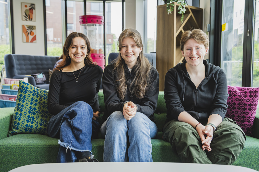 Three students sitting on a green sofa